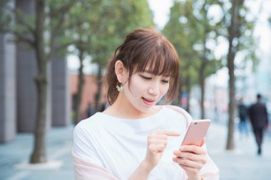 Akıllı telefon kullanan, fotoğraf çeken ve uygulamalar kullanan Asyalı bir kadın.