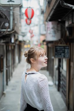 Tokyo 'da içki içilen bir yerde duran beyaz bir kadın.
