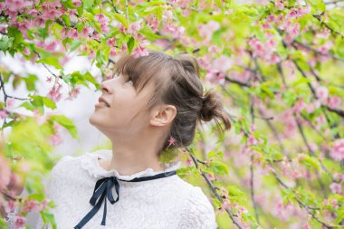 Taze yeşille çevrili, rahat bir ifade sergileyen beyaz bir kadın.