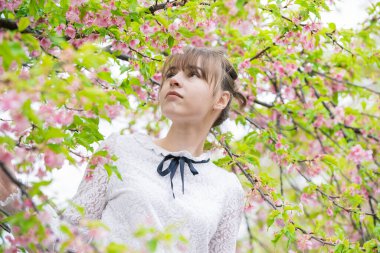 Taze yeşille çevrili, rahat bir ifade sergileyen beyaz bir kadın.