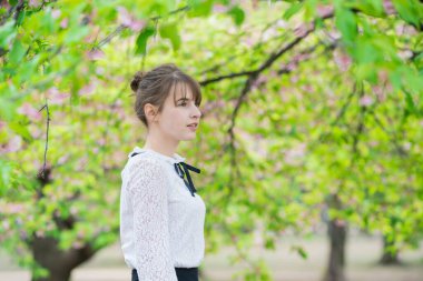 Taze yeşille çevrili, rahat bir ifade sergileyen beyaz bir kadın.