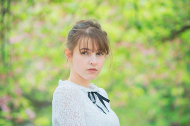 Taze yeşille çevrili, rahat bir ifade sergileyen beyaz bir kadın.