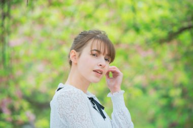 Taze yeşille çevrili, rahat bir ifade sergileyen beyaz bir kadın.