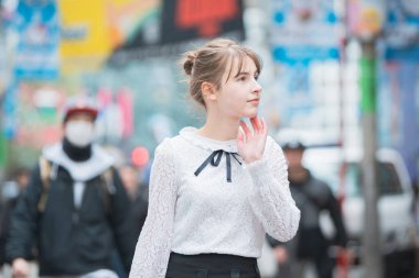 Genç Avrupalı kadın gülümseyerek Shibuya şehir merkezini (Tokyo, Japonya) geziyor.