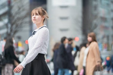 Genç Avrupalı bir kadın gülümseyerek Shibuya 'yı (Tokyo, Japonya) geçerken görüyor.