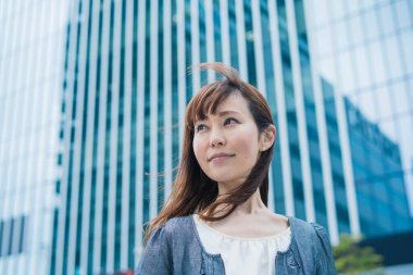Güneşli bir günde açık havada gülümseyen Asyalı (Japon) iş kadınının portresi