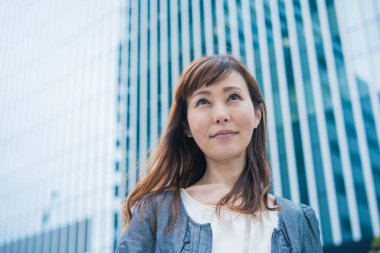 Güneşli bir günde açık havada gülümseyen Asyalı (Japon) iş kadınının portresi