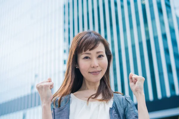 Asian (Japanese) female office worker posing strongly with both hands