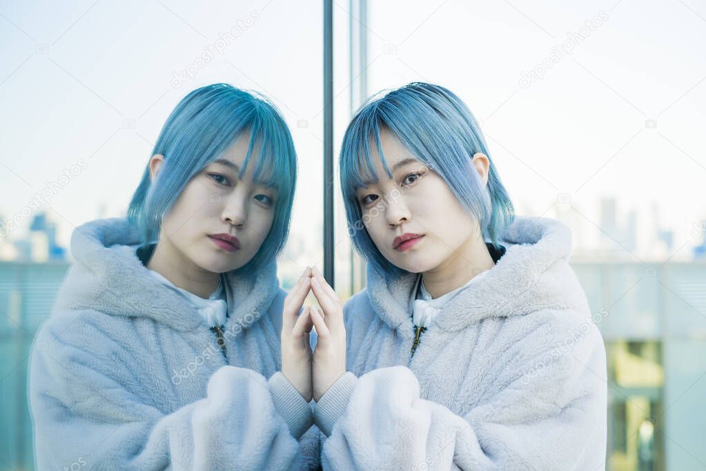 Young Asian (Japanese) woman with blue hair and her reflection