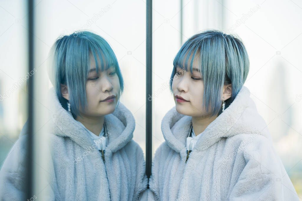 Young Asian (Japanese) woman with blue hair and her reflection