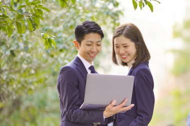 Takım elbiseli Asyalı işadamları dizüstü bilgisayara bakıyor.