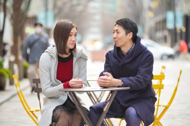 Asyalı (Japonca) genç aşıklar dışarıda konuşuyorlar ve gülüyorlar ve samimi olarak.