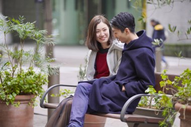 Asyalı (Japonca) genç aşıklar dışarıda konuşuyorlar ve gülüyorlar ve samimi olarak.