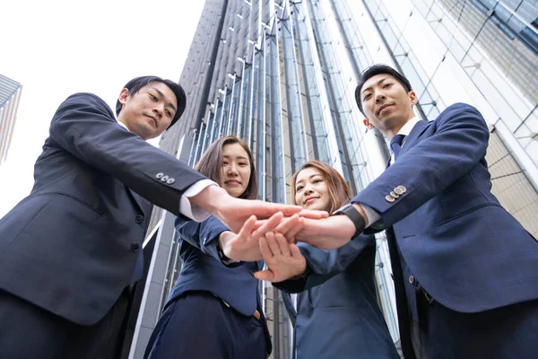 Business team of Asian men and women strengthening unity by overlapping hands