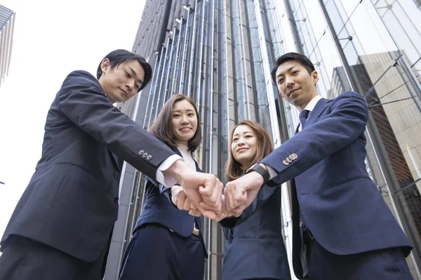 Business team of Asian men and women strengthening unity by overlapping hands