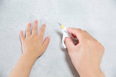 Anne tırnak makası kullanarak bebeğin elinin tırnağını kesti.