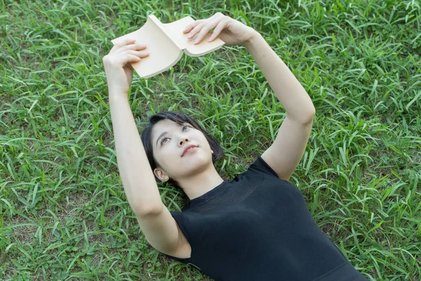 芝生のある公園で本を読む女子大生 — ストック写真