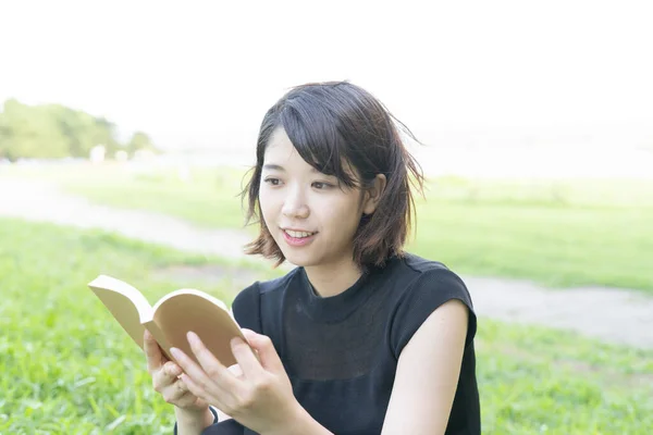 芝生のある公園で本を読む女子大生 — ストック写真