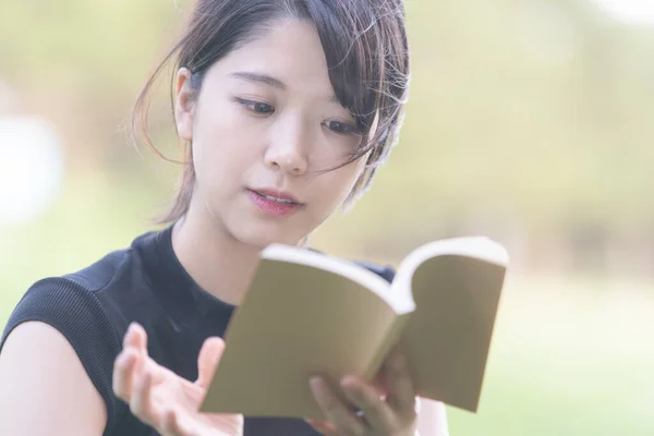 Asiática Japonesa Estudiante Universitaria Leyendo Libro Parque Con Césped Imagen de archivo