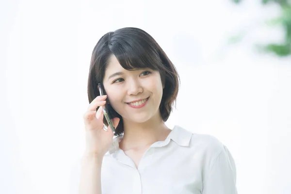 アジアの若い女性は耳にスマートフォンを持つ誰かと話して — ストック写真
