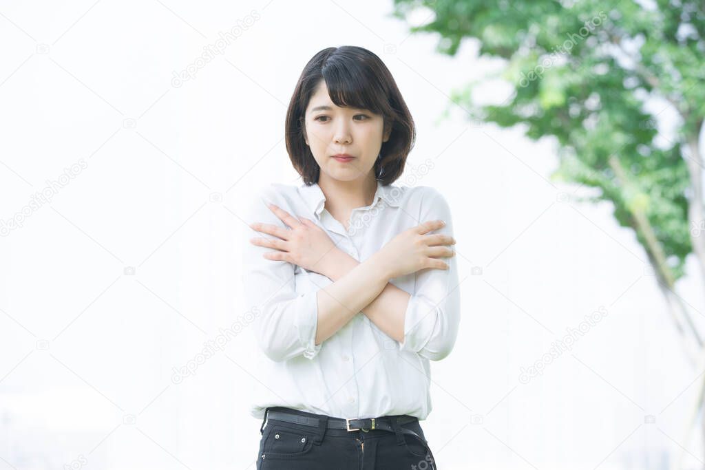 Asian (Japanese) young woman with a worried and anxious expression outdoors