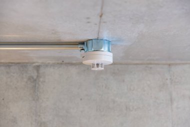 Yangın alarmı odadaki gri beton tavana monte edilmiş.
