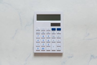 Beyaz mermerden yapılmış bir masaya yerleştirilmiş beyaz hesap makinesi