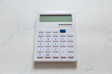 Beyaz mermerden yapılmış bir masaya yerleştirilmiş beyaz hesap makinesi