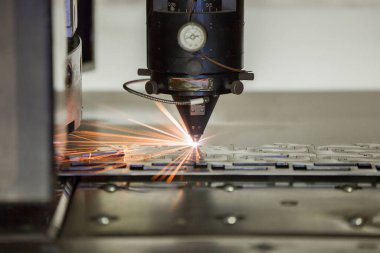 Fabrikada kıvılcımlar saçarak metal levhaları işleyen bir makine aracı.