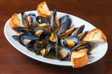 Midyeler beyaz şarap buğulama ve ahşap bir masada ekmek.