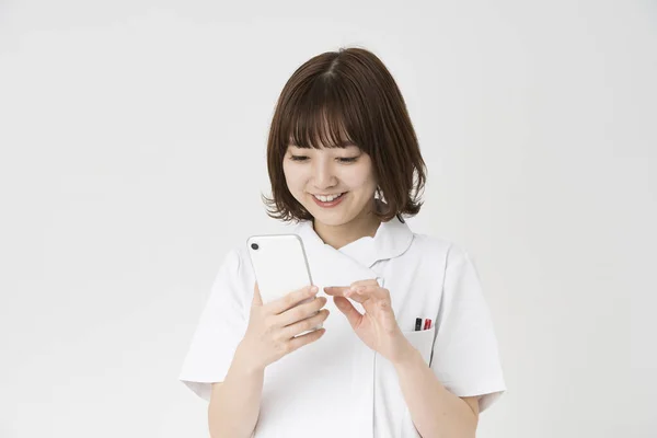 Asiatische Japanische Krankenschwester Sieht Einen Smartphone Bildschirm Mit Einem Lächeln — Stockfoto