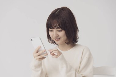 Akıllı telefon kullanan, fotoğraf çeken ve uygulamalar kullanan Asyalı bir kadın.