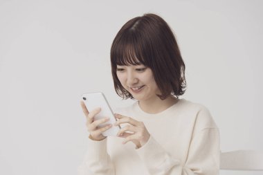 Akıllı telefon kullanan, fotoğraf çeken ve uygulamalar kullanan Asyalı bir kadın.