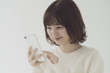 Akıllı telefon kullanan, fotoğraf çeken ve uygulamalar kullanan Asyalı bir kadın.