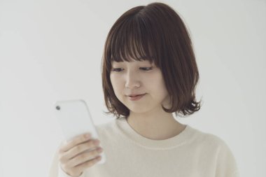 Akıllı telefon kullanan, fotoğraf çeken ve uygulamalar kullanan Asyalı bir kadın.