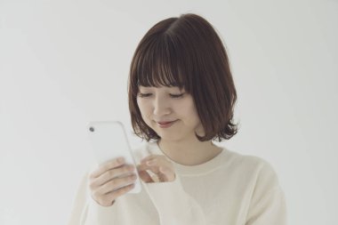 Akıllı telefon kullanan, fotoğraf çeken ve uygulamalar kullanan Asyalı bir kadın.