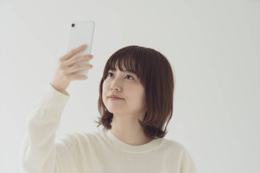Akıllı telefon kullanan, fotoğraf çeken ve uygulamalar kullanan Asyalı bir kadın.