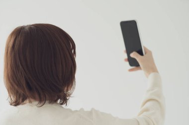 Akıllı telefon kullanan, fotoğraf çeken ve uygulamalar kullanan Asyalı bir kadın.