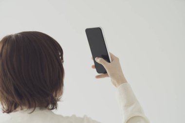 Akıllı telefon kullanan, fotoğraf çeken ve uygulamalar kullanan Asyalı bir kadın.