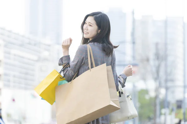 带着许多不同颜色的购物袋微笑的亚洲年轻女子 — 图库照片