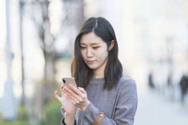 Akıllı telefon kullanan, fotoğraf çeken ve uygulamalar kullanan Asyalı bir kadın.