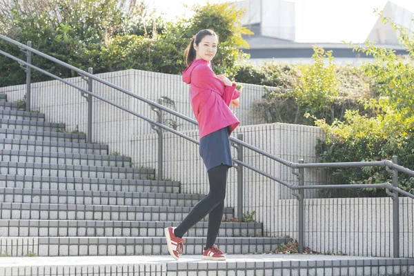 Asian young business woman exercising in the city center on a sunny day