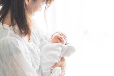 Yeni doğmuş bir Asyalı (Japon) bebeği taşıyan bir anne (0 yaşında) 0 aylık)