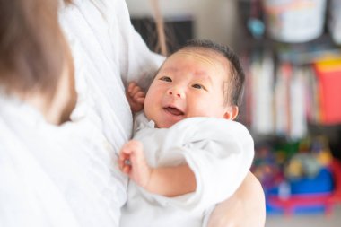 Yeni doğmuş bir Asyalı (Japon) bebeği taşıyan bir anne (0 yaşında) 0 aylık)