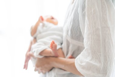 Yeni doğmuş bir Asyalı (Japon) bebeği taşıyan bir anne (0 yaşında) 0 aylık)