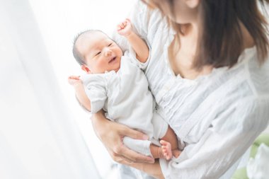 Yeni doğmuş bir Asyalı (Japon) bebeği taşıyan bir anne (0 yaşında) 0 aylık)