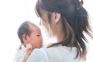 Yeni doğmuş bir Asyalı (Japon) bebeği taşıyan bir anne (0 yaşında) 0 aylık)