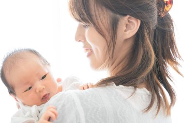 Yeni doğmuş bir Asyalı (Japon) bebeği taşıyan bir anne (0 yaşında) 0 aylık)