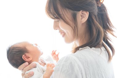 Yeni doğmuş bir Asyalı (Japon) bebeği taşıyan bir anne (0 yaşında) 0 aylık)