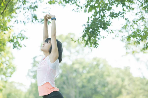 Asian woman taking a deep breath during exercise in the park